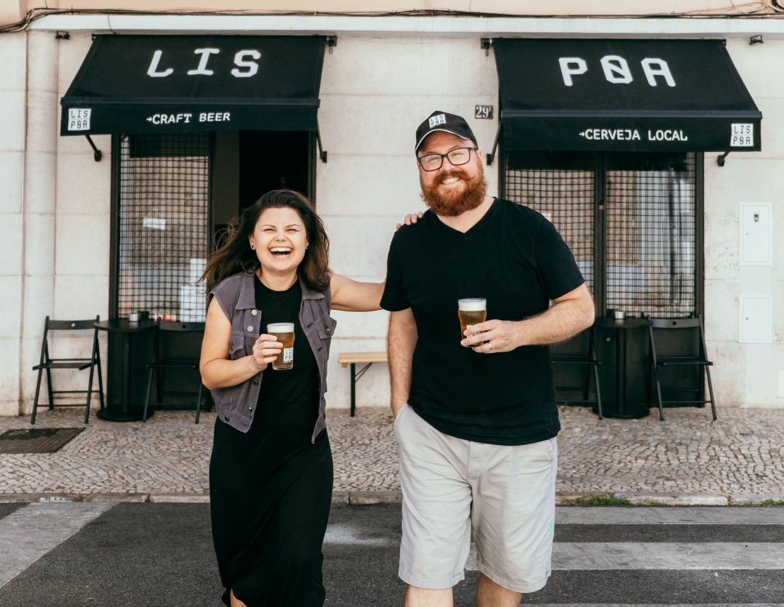 Luciana e Tarlis na frente da LisPoa com cervejas na mão.